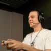 A man plays on a games console wearing the Meze Audio 99 NEO headset with Boom Mic