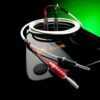 Two red and black audio connectors plugged into a coiled white cable on a glossy surface with a green/black background.