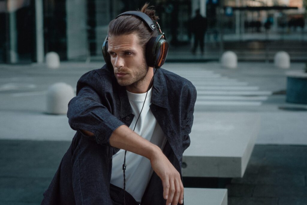 meze-strada-new-headphones - MGY OU A person on a becnh in urban environment is listening to music in beautifully crafted Meze STRADA new headphones