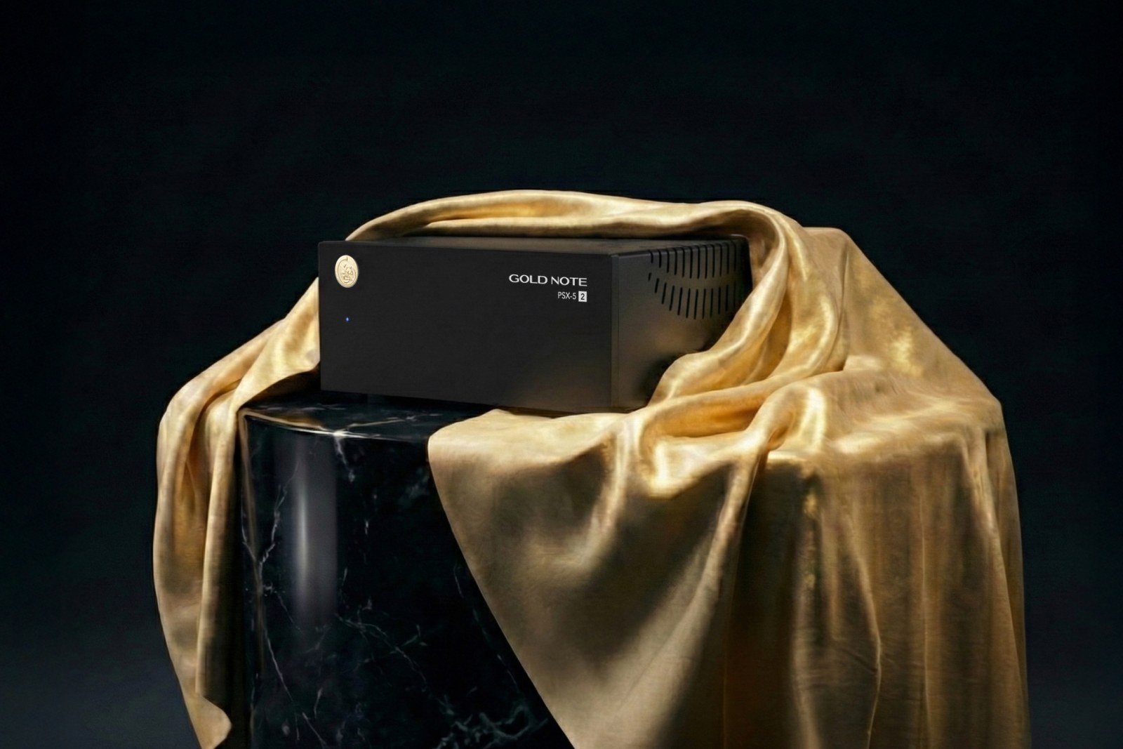 Gold Note PSX-5.2, jauns barošanas avots Gold Note 5.2 audio elektronikas klāstam prezentācijā; ierīce novietota uz marmora kolonnas un pārklāta ar izsmalcinātu zelta audumu
