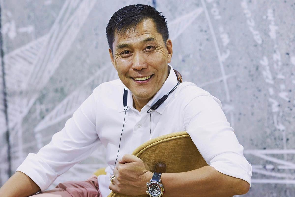 Xiaodong Yan, Cinemaster’s CEO, is smiling at the camera, wearing a white shirt and seated on a chair